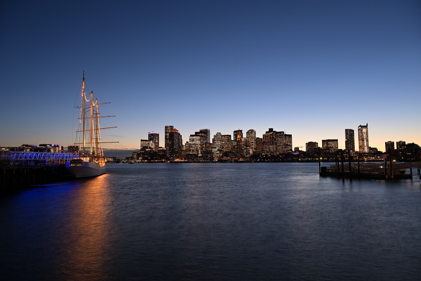 Boston's skyline and a tall ship on the harbor at dusk